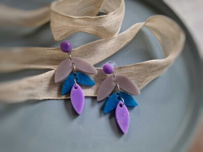 Es ist die hamonische Farbkomination von Lila, Grau und durchleuchtendem Blau mit lässigen, floralen Tropfenanhängern, die diese handgefertigten Schmuckunikate zu wunderschönen elegant verspielten Ohrringen machen.