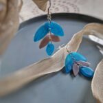 Es ist die hamonische Farbkomination von Lila, Grau und durchleuchtendem Blau mit lässigen, floralen Tropfenanhängern, die diese handgefertigten Schmuckunikate zu wunderschönen elegant verspielten Ohrringen machen.