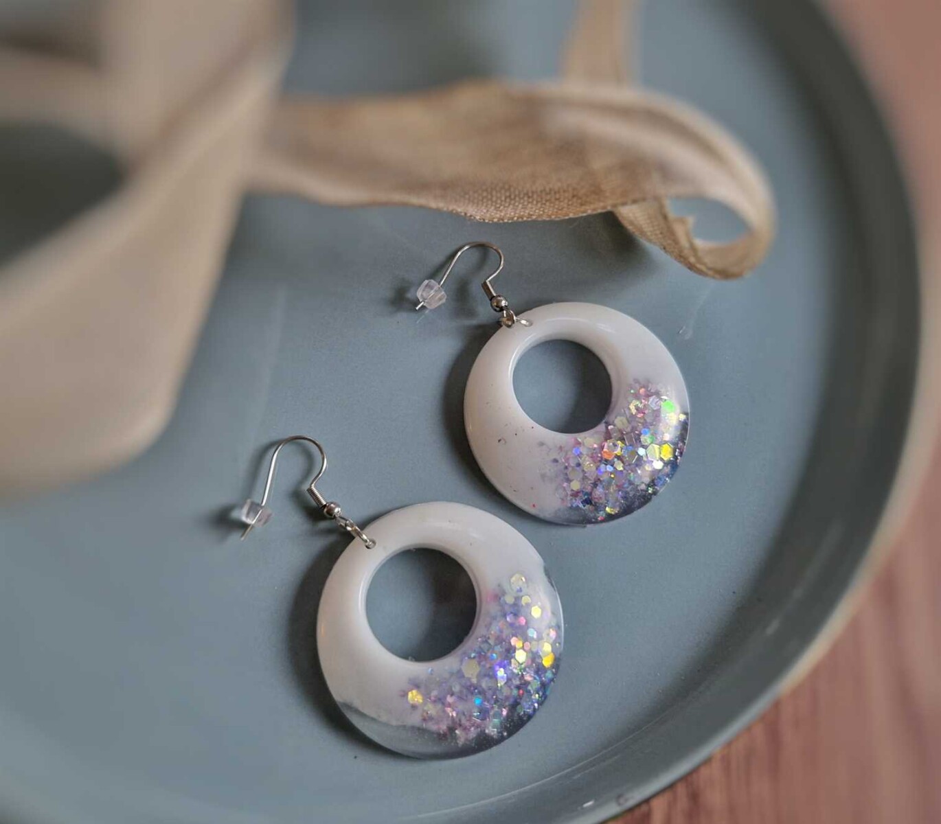 Die weißen runden Boho-Ohrringe punkten durch ihre glänzende Form und die tollen harmonierenden silbernen Glitzerpartikel. Echte handgefertigte Kunstohrringe.