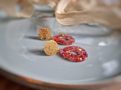 Runde goldene Ornamentohrstecker mit lachs- bzw. pfirsichfarbene Glitzerpailletten Ohrringe in Tropfenform.