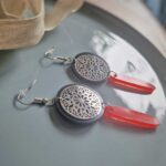 Die handmade flachen runden schwarzen Ohrhänger mit zierlicher silberner Ornament-Platte und rotem Anhänger verzaubern mit ihrer orientalischen Zartheit.
