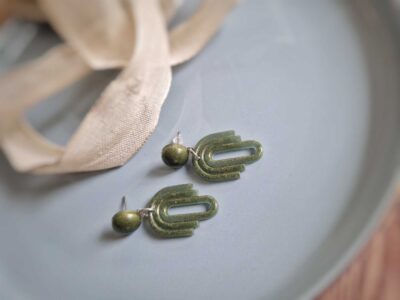 Die handmade flachen Ohrhänger mit zierlichen olivfarbenen Ohrsteckern verzaubern mit ihrer fließenden Formsprache.