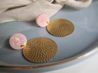 Unter den runden elegant glitzernden rosa Ohrsteckern hängen hauchzarte goldene Kreisohrhänger in Rattan-Optik aus Metall und geben diesen romantischen eleganten Ohrringen das romantische Etwas.