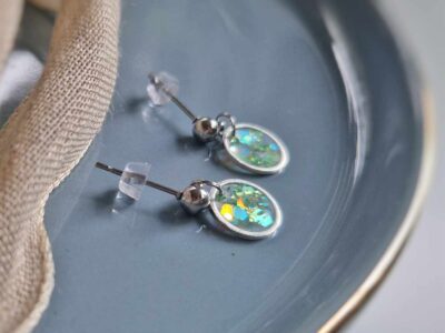 In eine hauchzarte Kreislünette wurde in transparentem Resin pastellgrüne Glitzerpartikel gegossen. Vornehme, handgefertigte Eleganz.