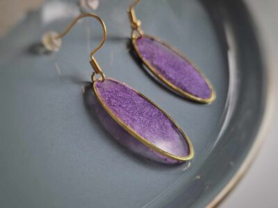 Diese elfenhaften transparenten ovalen Ohrringe in goldener Lünette funkeln und leuchten herrlich in einem pudrigen Violett und sorgen für einen eleganten Auftritt.