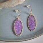 Diese elfenhaften transparenten ovalen Ohrringe in goldener Lünette funkeln und leuchten herrlich in einem pudrigen Violett und sorgen für einen eleganten Auftritt.