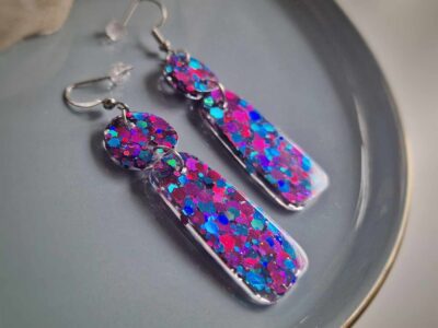 In den transparenten organic-Anhängern wurden glitzernde pink-blaue Pailletten gegossen, die je nach Lichteinfall strahlend leuchten