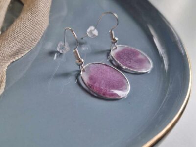 In eine hauchzarte silberne Kreislünette wurde mit transparenten Resin violettes Puder gegossen, um diese elegante Farbkomposition zu kreieren.