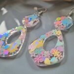 In den transparenten großzügen Boho-Anhängern wurden glitzernde Blumen- und Muschel-Pailletten in sommerlichen Pastelltönen gegossen, die je nach Lichteinfall strahlend türkis-changierend leuchten, Akzente setzen und diese Statementohrringe zu  individuellen Begleitern machen.  Echte handgefertigte Kunstohrringe