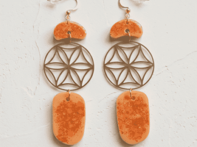 Boho-Ohrhänger „Lebensenergie“ mit Blume des Lebens – OrangeSpüre die harmonisierende Kraft der heiligen Geometrie. Diese kunstvollen Ohrhänger vereinen das kraftvolle Symbol der Blume des Lebens mit der lebendigen Energie von warmem Orange. Die sanft geschwungenen, gesprenkelten Kunstharz-Elemente (Resin) erinnern an organische Kieselsteine und verleihen dem Schmuckstück eine natürliche, erdige Note. Ein absolutes Statement-Piece für Freigeister, das jedem Outfit eine spirituelle und zugleich stilvolle Ausstrahlung verleiht. Handgefertigt für deine Einzigartigkeit.