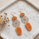 Boho-Ohrhänger „Lebensenergie“ mit Blume des Lebens – OrangeSpüre die harmonisierende Kraft der heiligen Geometrie. Diese kunstvollen Ohrhänger vereinen das kraftvolle Symbol der Blume des Lebens mit der lebendigen Energie von warmem Orange. Die sanft geschwungenen, gesprenkelten Kunstharz-Elemente (Resin) erinnern an organische Kieselsteine und verleihen dem Schmuckstück eine natürliche, erdige Note. Ein absolutes Statement-Piece für Freigeister, das jedem Outfit eine spirituelle und zugleich stilvolle Ausstrahlung verleiht. Handgefertigt für deine Einzigartigkeit.