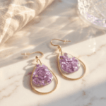 Um die transparent-violetten Tropfenanhänger funkeln zarte goldene Edelstahl-Lünetten, die je nach Lichteinfall elegant glänzen und diese Tropfenohrringe zu  individuellen Begleitern machen. 