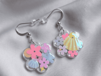In den transparenten Blumen-Anhängern wurden glitzernde Blumen- und Muschel-Pailletten in sommerlichen Pastelltönen gegossen, die je nach Lichteinfall strahlend türkis-changierend leuchten, Akzente setzen und diese Statementohrringe zu  individuellen Begleitern machen. 