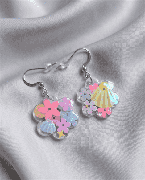In den transparenten Blumen-Anhängern wurden glitzernde Blumen- und Muschel-Pailletten in sommerlichen Pastelltönen gegossen, die je nach Lichteinfall strahlend türkis-changierend leuchten, Akzente setzen und diese Statementohrringe zu individuellen Begleitern machen.