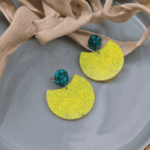 Geometrische Statement-Ohrringe „Neon Breeze“ in Gelb & SmaragdgrünKontraste, die begeistern! Diese auffälligen Hängeohrringe vereinen minimalistische, geometrische Formen mit einer explosiven Farbkombination. Das große, halbkreisförmige Element in leuchtendem Zitronengelb besticht durch seine fein strukturierte Oberfläche. Als eleganter Gegenpol dient der runde Stecker, der mit tiefgrünen Glitzerpartikeln besetzt ist und das Licht faszinierend bricht. Perfekt, um schlichten Outfits im Handumdrehen ein modisches Upgrade zu verpassen.