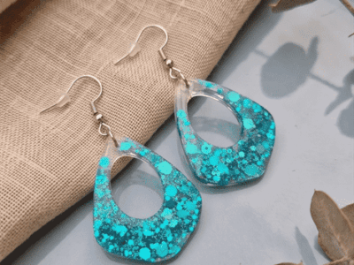 Statement-Ohrringe „Ocean Glitter“ – Türkises Konfetti in klarem ResinHol dir das Urlaubsgefühl direkt nach Hause! Diese ausdrucksstarken Ohrhänger fangen das Licht bei jeder Bewegung ein und erinnern an das glitzernde Wasser einer tropischen Lagune. Der harmonische Verlauf von klarem Harz zu dichtem, türkisblauem Glitzer verleiht dem Schmuckstück eine faszinierende Tiefe. Das perfekte Accessoire für sommerliche Outfits, Strandkleider oder deinen nächsten Festival-Look.