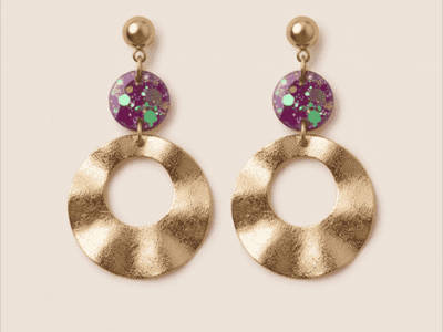 Statement-Ohrringe „Purple Galaxy“ mit gewellten Goldringen & GlitzerLass dich von kosmischer Eleganz verzaubern! Diese ausdrucksstarken Hängeohrringe fangen das Licht bei jeder Bewegung faszinierend ein. Die großen, organisch gewellten Ringe in mattem Goldton bringen eine edle, fließende Dynamik in dein Outfit. Als farbintensiver Blickfang dienen die runden Elemente in tiefem Violett, die mit feinsten holografischen Glitzerpartikeln und Pailletten durchsetzt sind. Ein luxuriöser Hingucker für glamouröse Abend-Looks oder um schlichte Alltags-Outfits stilvoll aufzuwerten.