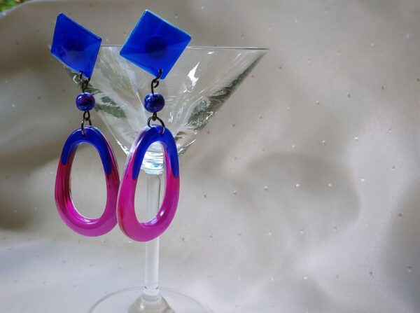 Dieses Paar Ohrringe wurde in einem tiefen Asterblau und transparenten Blau und Pinktönen gegossen. Als Verbinder wurde eine edle Glasperle eingearbeitet.