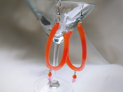 Hier treffen die zwei Gute-Laune -Farben Orange und Pink aufeinander und kreieren mit den verspielten Kunststoff-Perlen einen hinreißend fröhlichen Charme.
