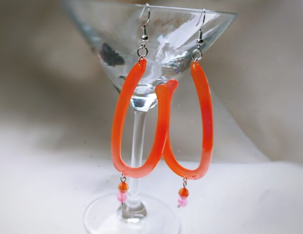 Hier treffen die zwei Gute-Laune -Farben Orange und Pink aufeinander und kreieren mit den verspielten Kunststoff-Perlen einen hinreißend fröhlichen Charme.