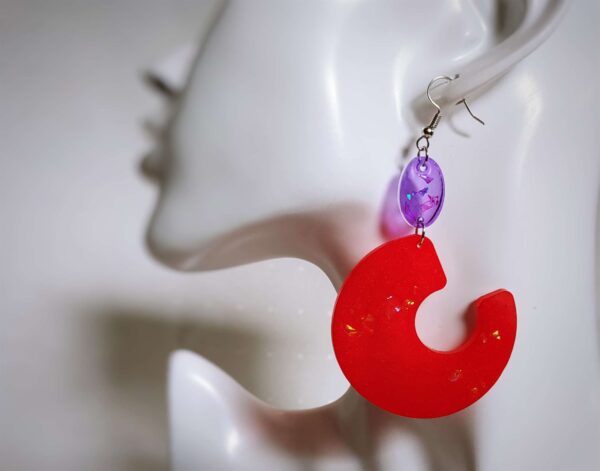 Die auffälligen hauchdünnen Ohrringe strahlen in einem schimmernden Rosenrot und werden von violetten Plättchen gehalten. Die Glitzerfolien im Inneren sorgen für Glanzmomente