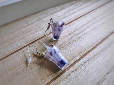 Diese zierlichen Ohrhänger zeigen sich von ihrer spritzigen Seite und präsentieren einen lila Cocktail á la "Purple Rain" im Glas.