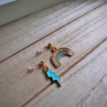 Diese zierlichen Ohrhänger zeigen sich von ihrer nostalgischen Retroseite und präsentieren einen Regenbogen á la Regina Regenbogen und einen hellblauen Blitz.