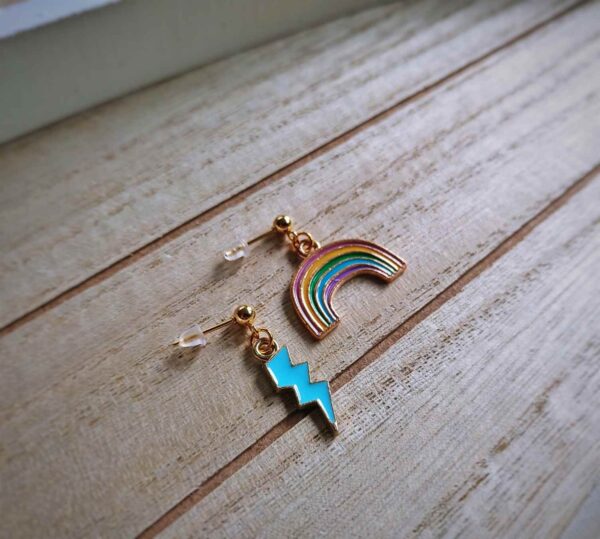 Diese zierlichen Ohrhänger zeigen sich von ihrer nostalgischen Retroseite und präsentieren einen Regenbogen á la Regina Regenbogen und einen hellblauen Blitz.