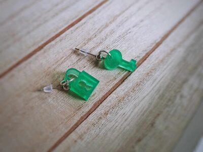 Die knallgrünen zierlichen Ohrstecker in Schlüssel und Schlossform setzen peppige Akzente.