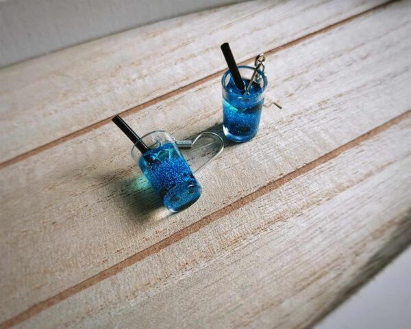 Diese zierlichen Ohrhänger zeigen sich von ihrer spritzigen Seite und präsentieren einen blauen Cocktail á la "blaue Lagune" mit Eiswürfeln im Glas.
