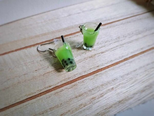 Diese zierlichen Ohrhänger zeigen sich von ihrer spritzigen Seite und präsentieren einen Bubble Tea mit grünem Inhalt im Glas.