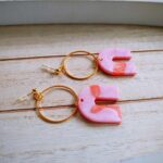 An wunderschön goldglänzenden Ohrsteckern hängen goldene zierliche Kreise, an denen die sehr flachen creme-rosafarbenen Bogenhänger baumeln. Elegante Boho-Ohrhänger.