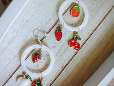 An zarten, flachen weißen Kreisohrhänger hängen rote Früchte wie Kirschen und Erdbeeren und sorgen für den außergewöhnlichen Hippie-Charme. Artsy-Ohrringe mal anders.