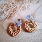 Mit einem transparenten Resinohrstecker mit hellblauem Inlay und einem geflochtenen Rattankreis präsentieren sich diese schönen hellen runden Ohrringe im Boho- oder Hippiestil.