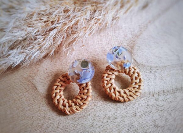 Mit einem transparenten Resinohrstecker mit hellblauem Inlay und einem geflochtenen Rattankreis präsentieren sich diese schönen hellen runden Ohrringe im Boho- oder Hippiestil.