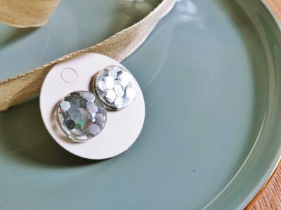 Diese handgefertigten runden Ohrstecker setzen auf eine funkelnd-elegante Weise Akzente und überzeugen durch silbernes Pailletten-Glitzer.