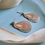 Über den hauchzart gegossenen altrosa ovalen Lünetten Ohrhängern bewegen sich filigrane tropfenförmige Ornamentohrringe mit orientalischer Anmut.
