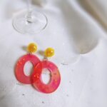 Die ovalen, sehr flachen Ohrringe wurden in den transparenten Gute-Laune-Farbtönen Gelb und Pink gefertigt und versprühen einen frischen Charme. Dank der integrierten kleinen Blumenmotive glitzert und funkelt es zusätzlich am Ohr. 
